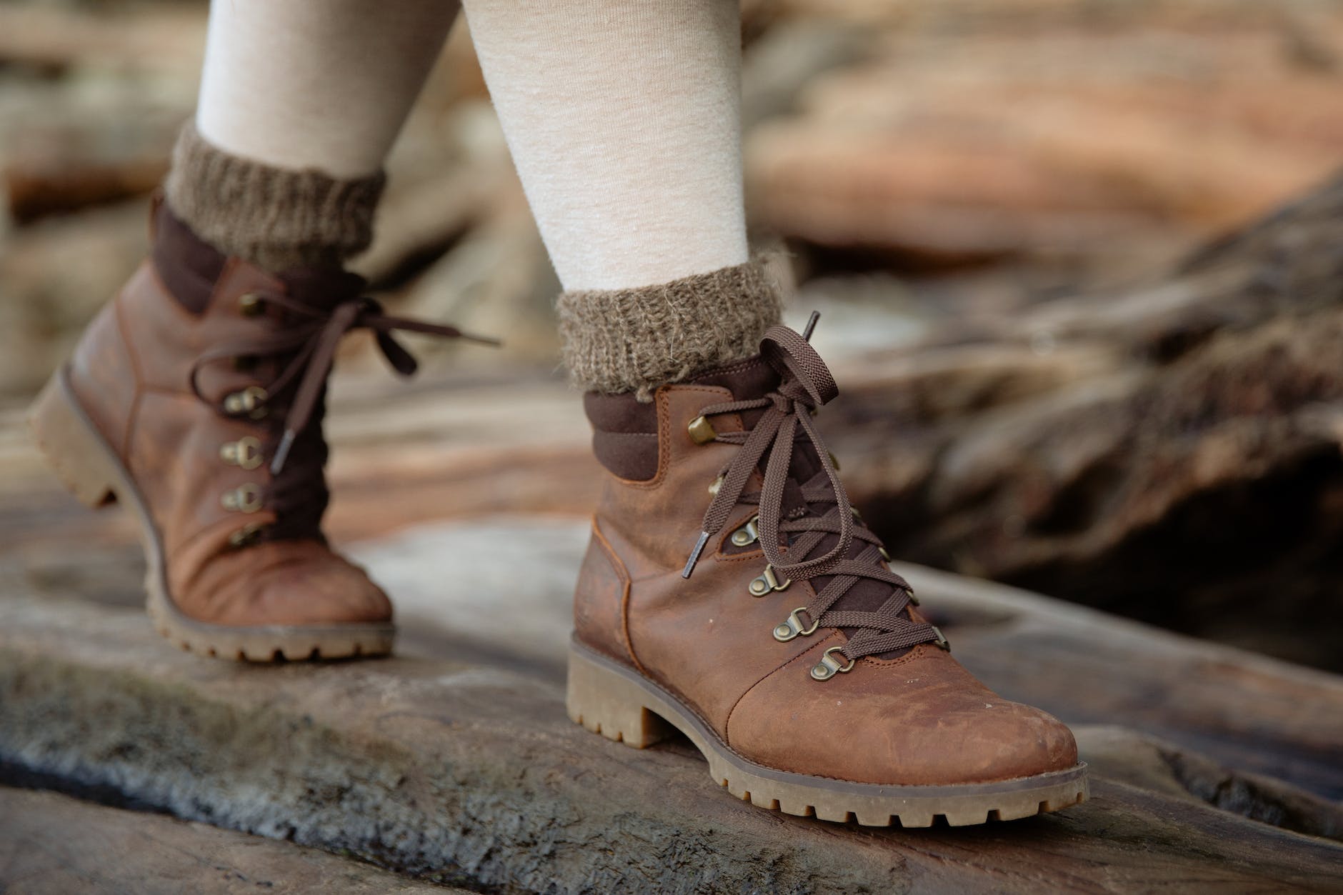 crop person in autumn boots walking on wet wooden logs