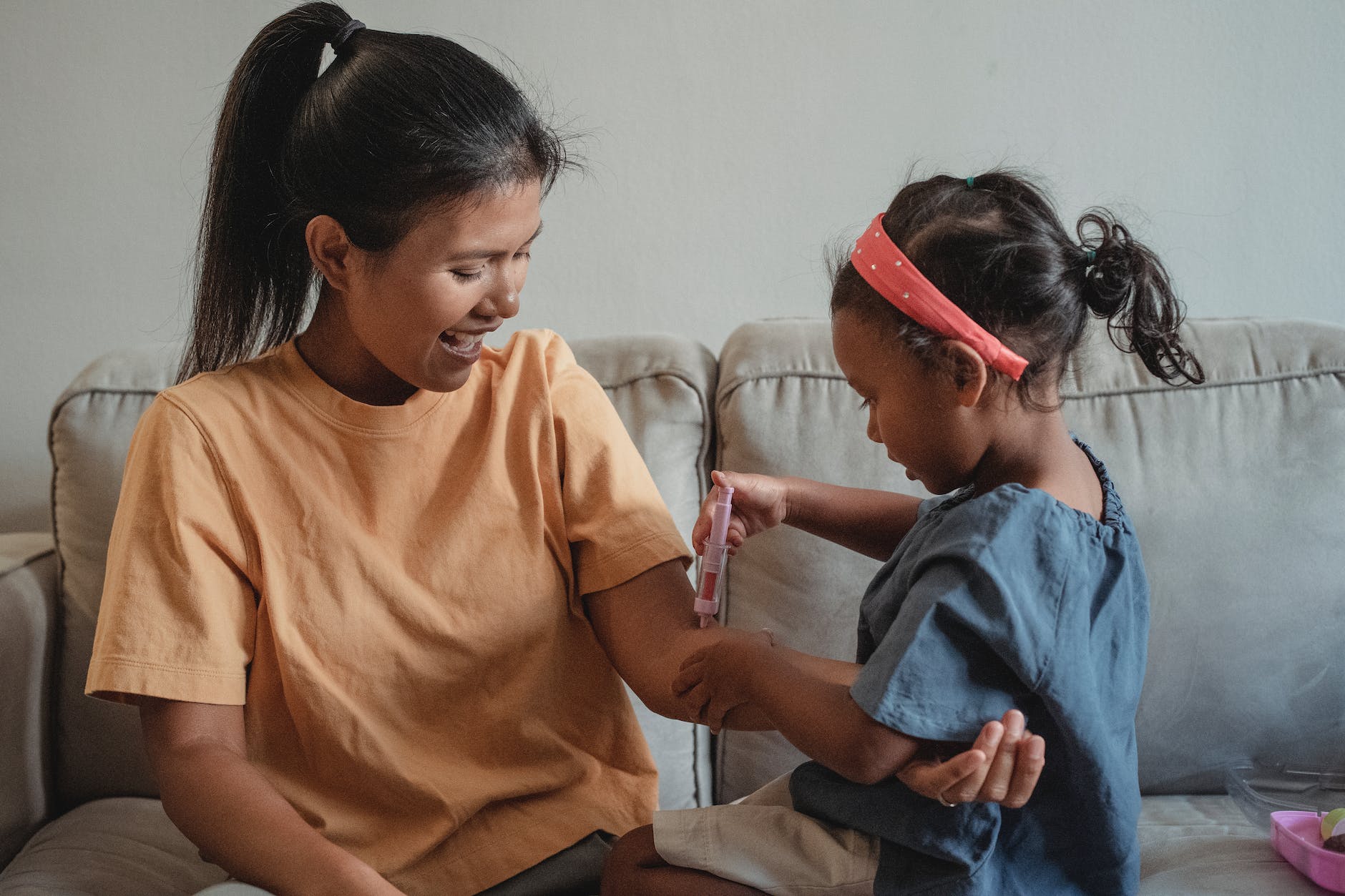ethnic mother and daughter playing with toy syringe