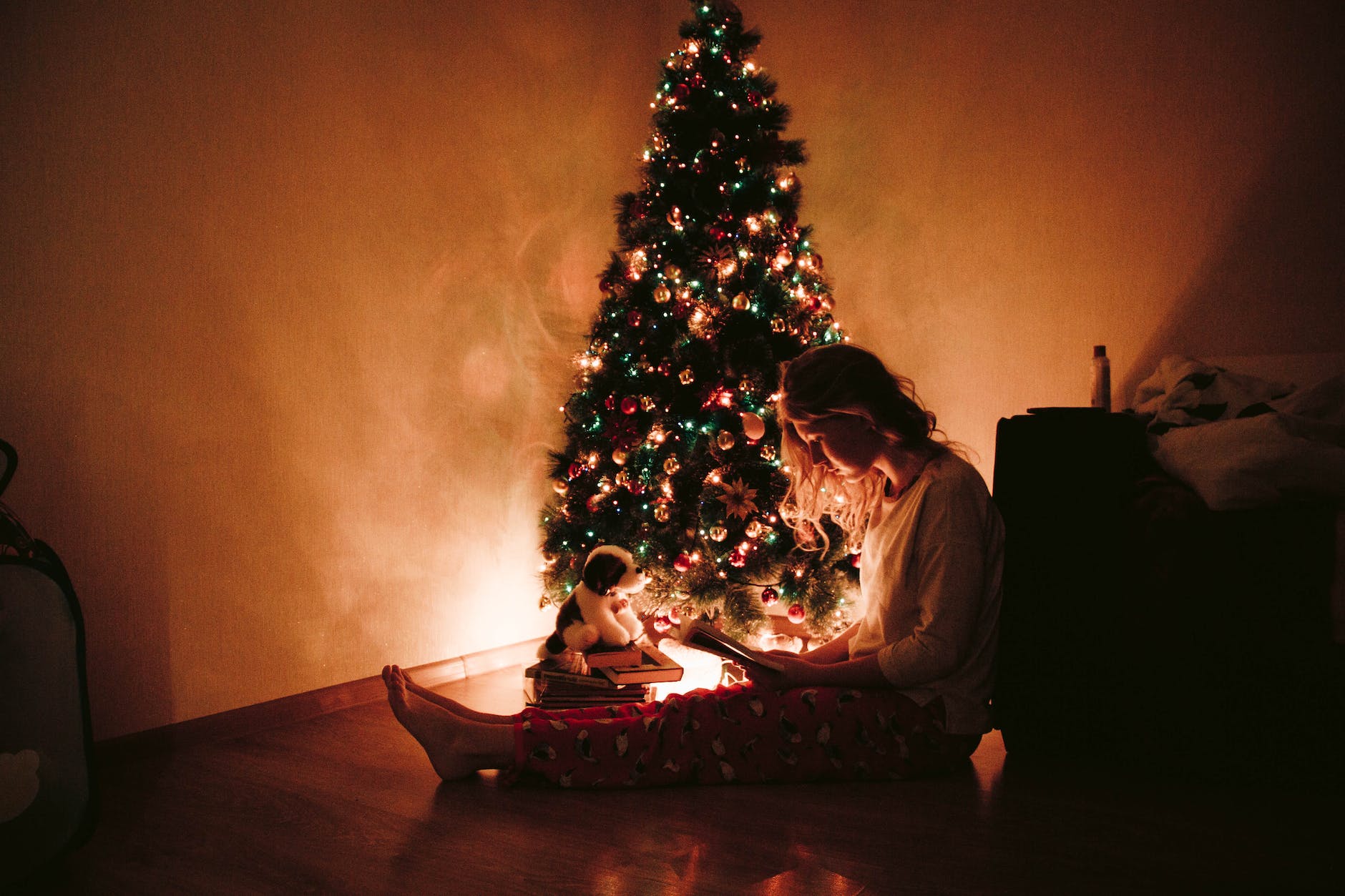 photo of woman sitting near the christmas tree