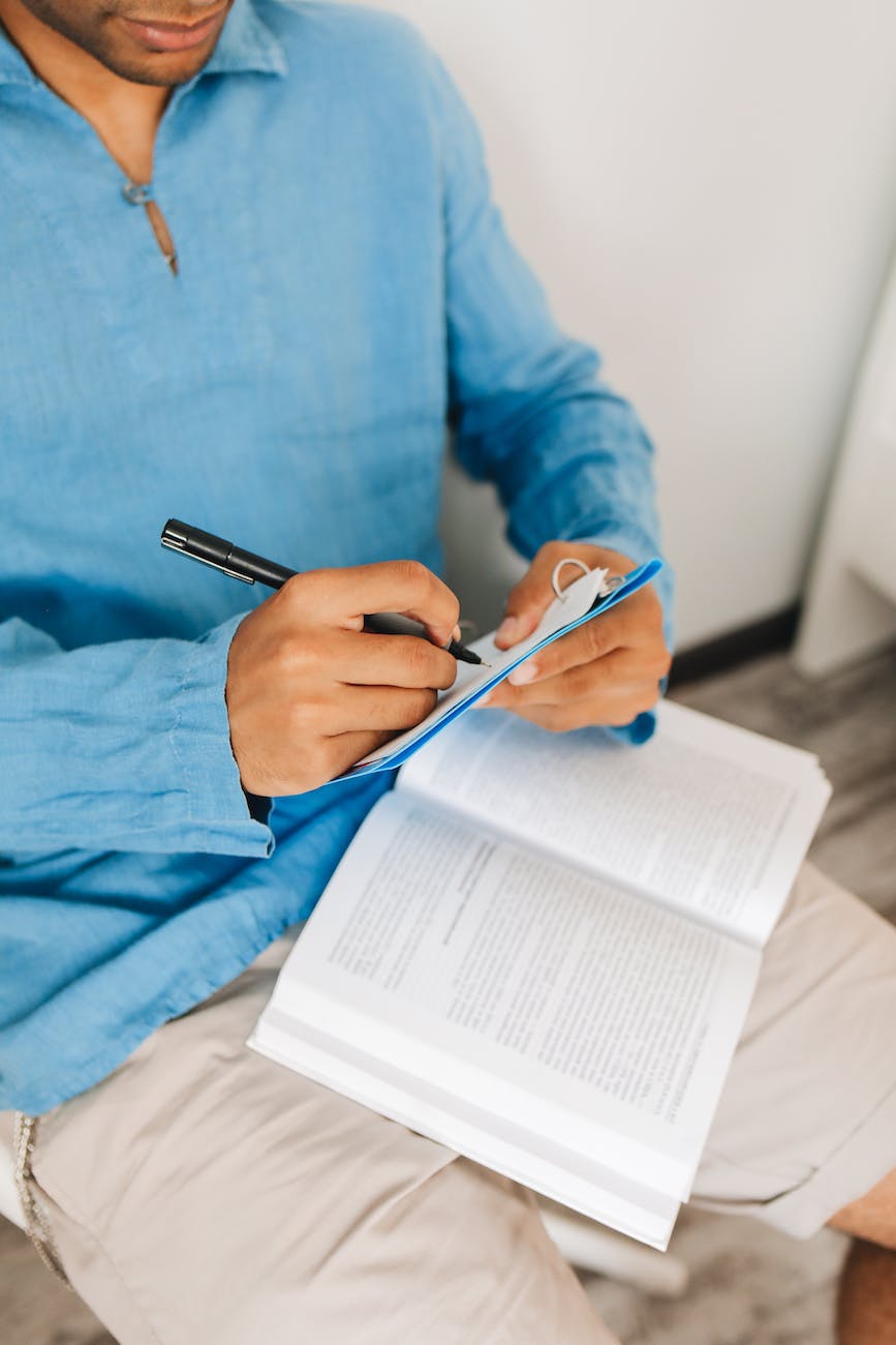 person in blue long sleeve shirt writing on a notebook