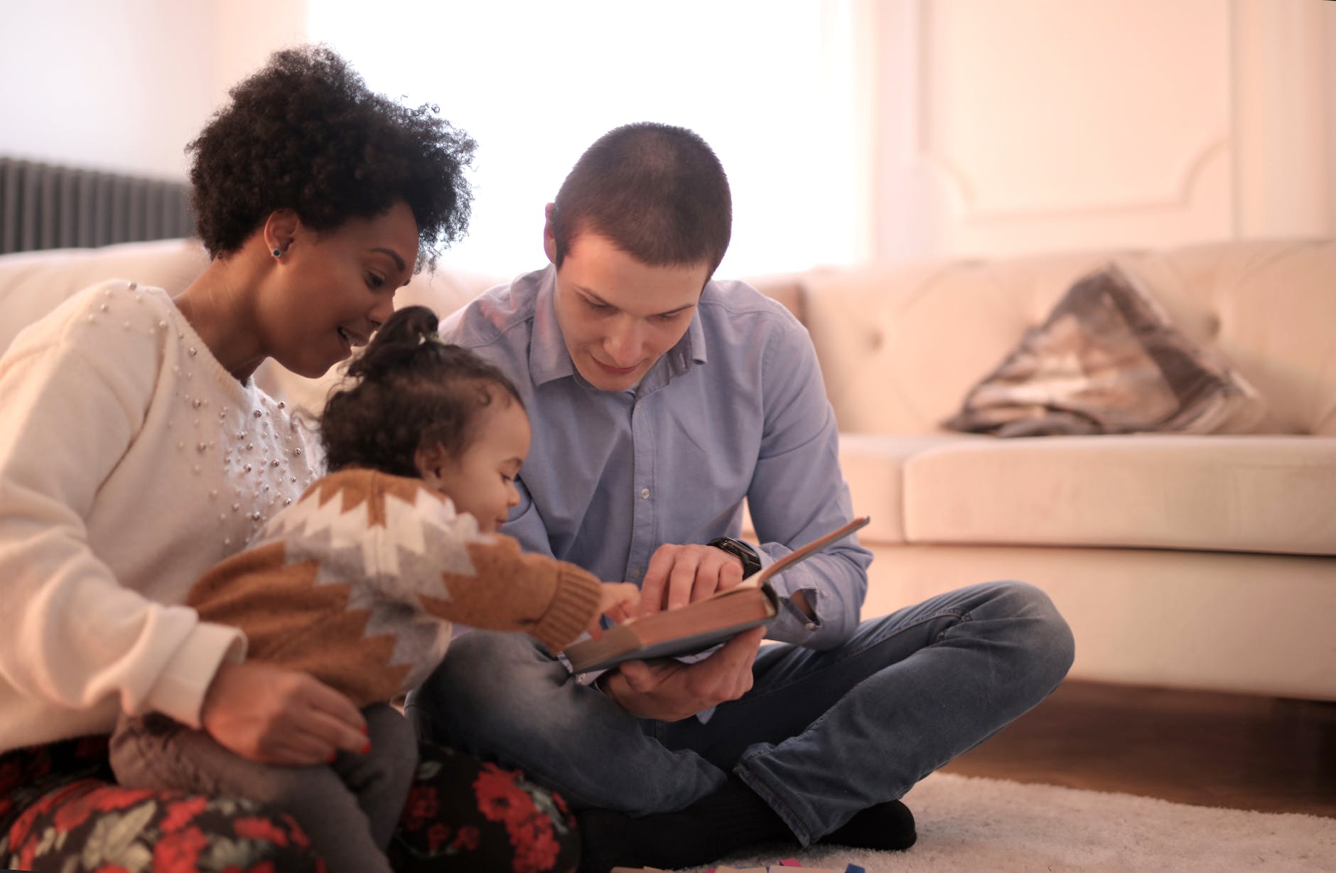 photo of family sitting on floor while reading book